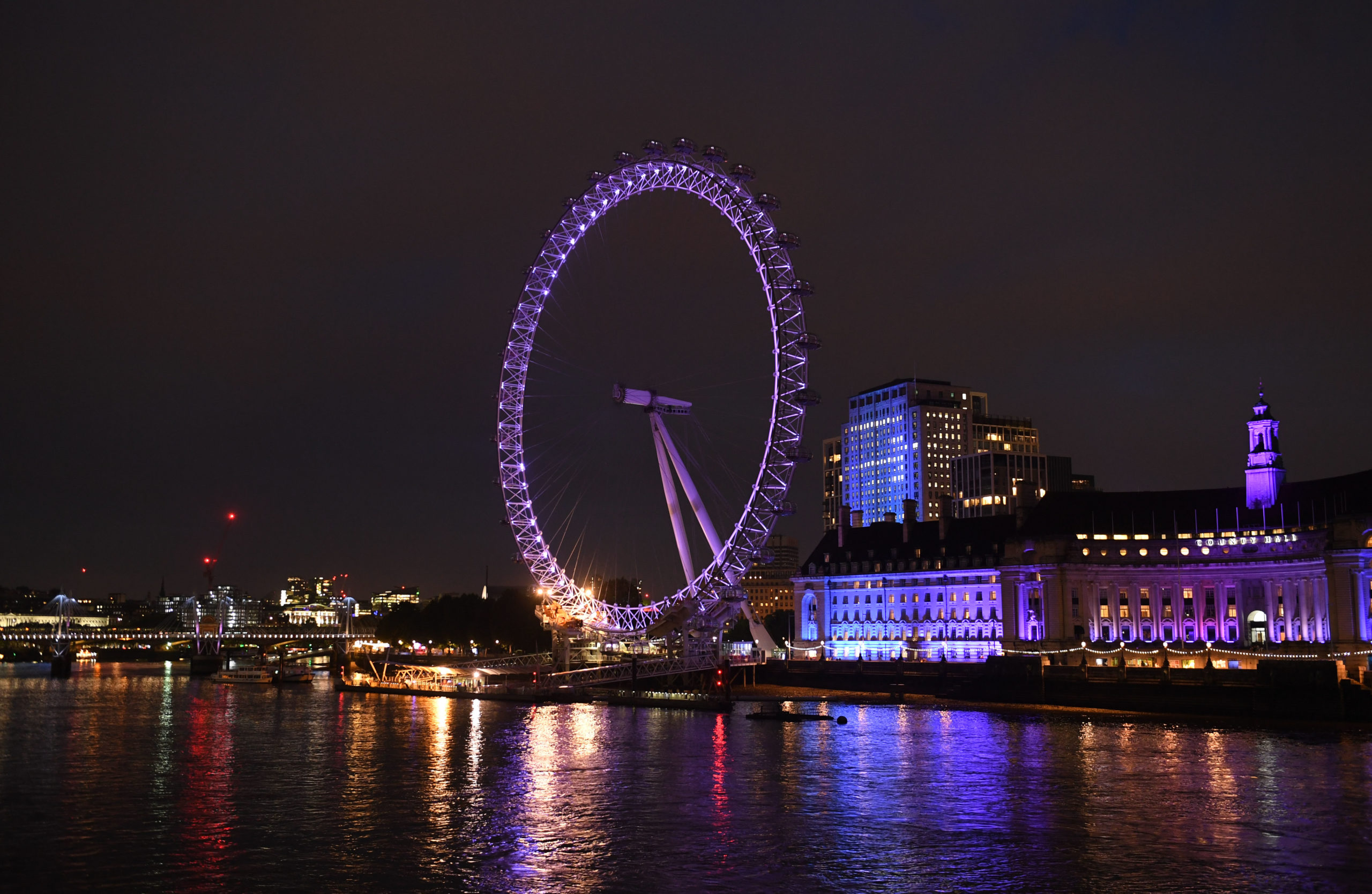 Photograph of the lastminute.com London Eye, illuminated in purple at night.