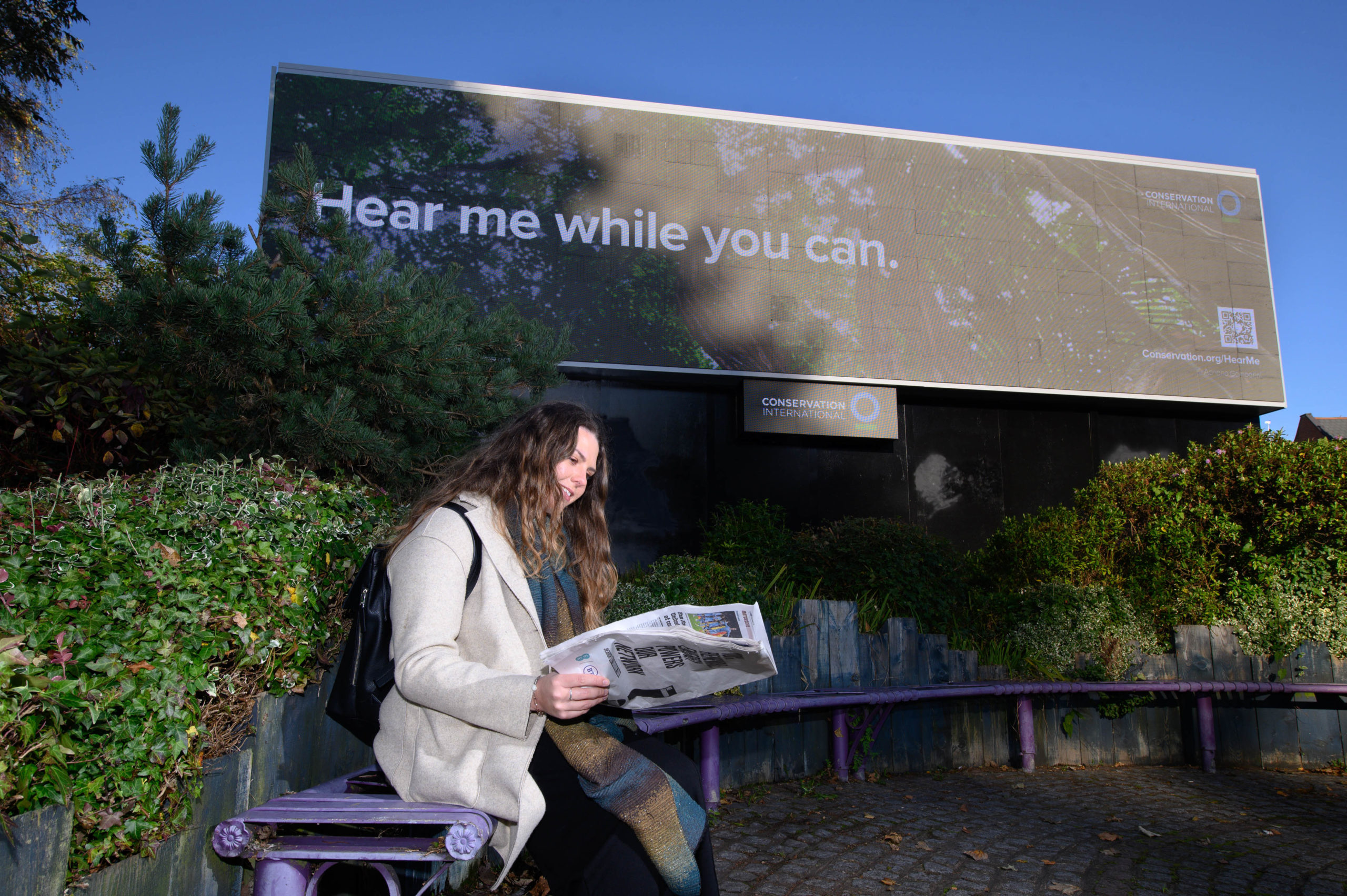 Gabrielle Roberts sits in front a new billboard unveiled by Conservation International in partnership with Clear Channel to launch their ‘Hear me while you can’ campaign, which was created to raise awareness of the importance of nature in our fight against climate change, London. Picture date: Friday November 5, 2021. PA Photo. The digital screens, which are being launched during COP26 in 26 countries in Europe, Asia and the Americas, feature a QR code which directs the public to the conservation charities website where they can listen to natural soundscapes — from the Amazon rainforest, the South African savannah, Southeast Asia mountains and the North Pacific Ocean, and learn more about Conservation International’s work to protect nature around the world.