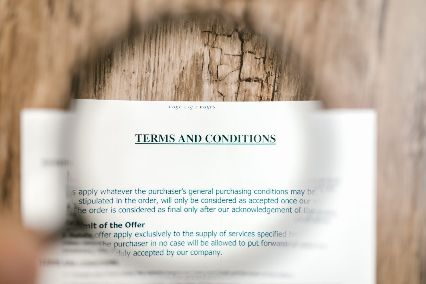 A magnifying glass enlarging the terms and conditions written on a paper contract