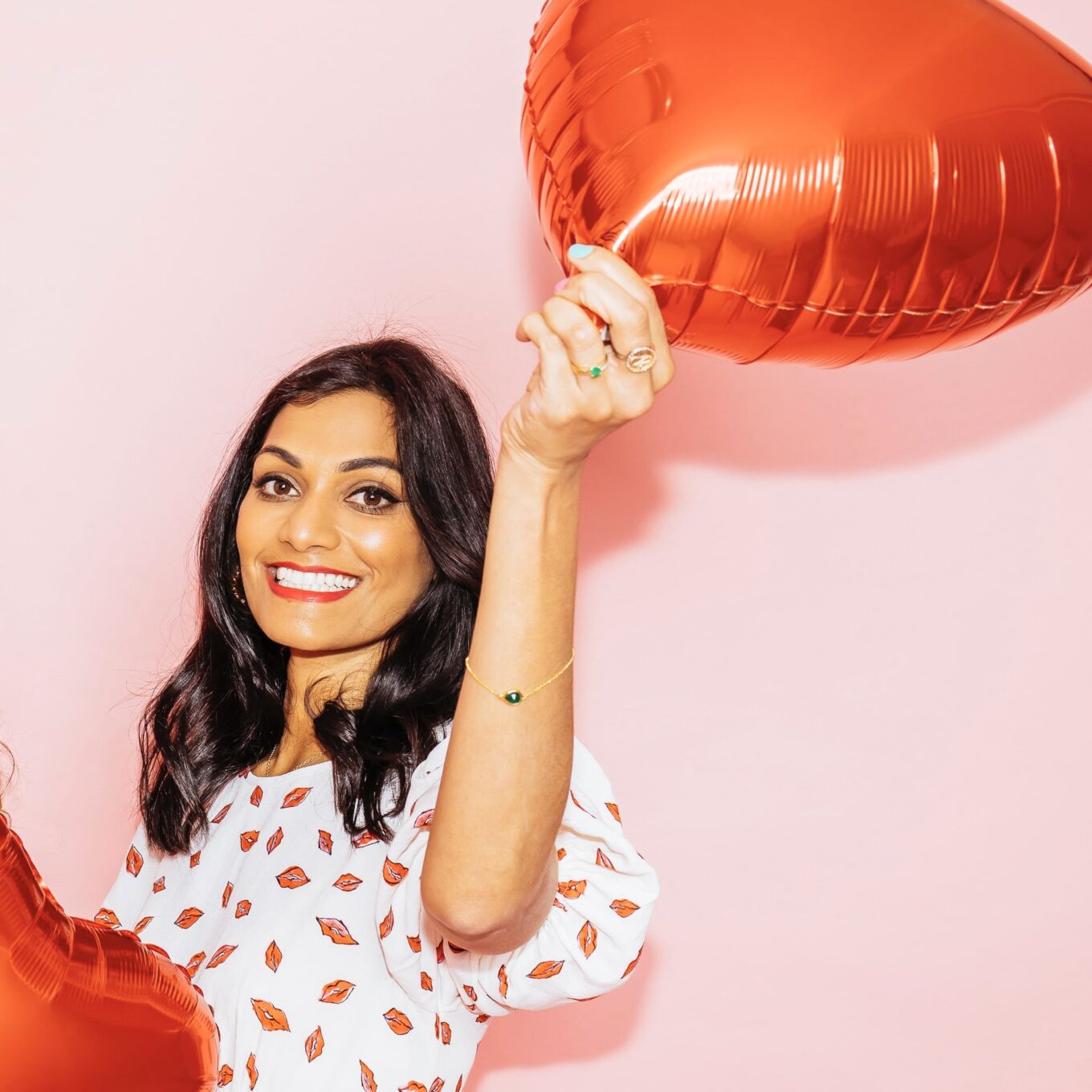 Vijaya Varilly smiling holding two heart shaped balloons