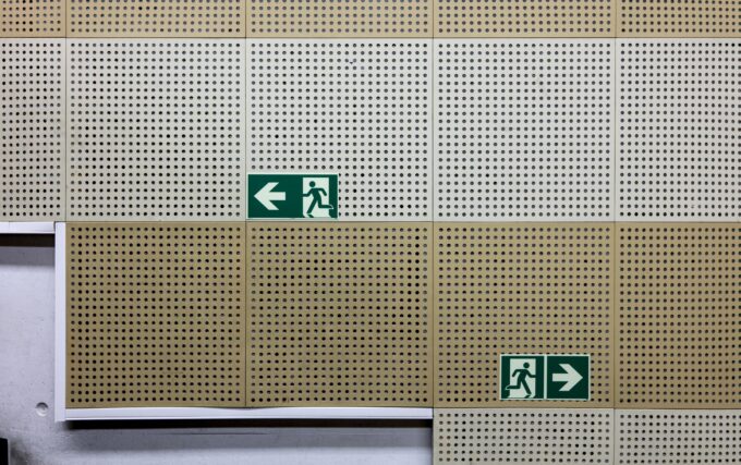 Exit signs on a wall pointing in different directions