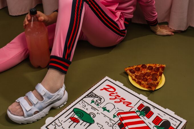 Person sitting on the floor with pizza and soda